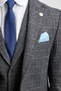 Gray checkered suit with blue tie and pocket square on a light gray background